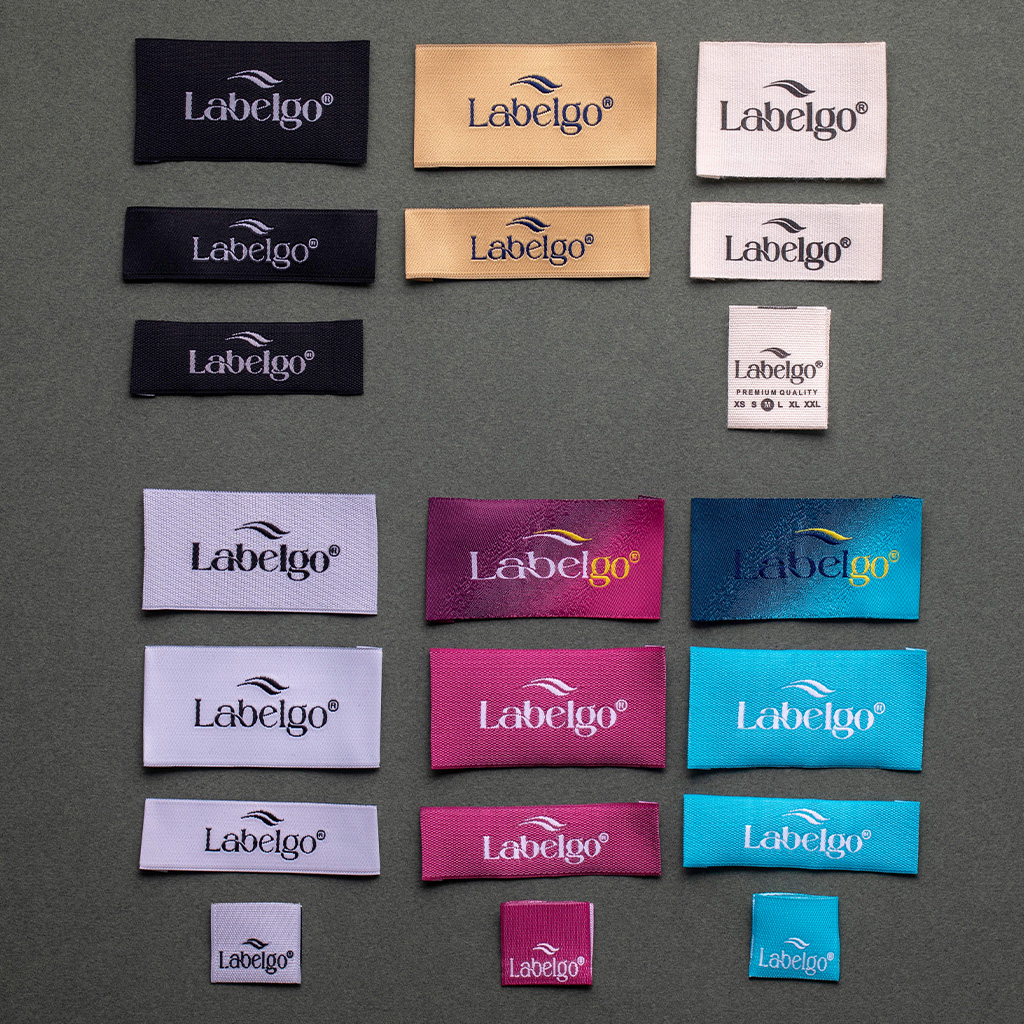Assorted colorful woven labels spread on fabric surface.